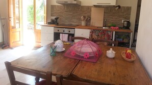 A kitchen with wooden cabinets, a stove, and a window. - TRULLO in an evergreen olive grove in Salento, Apulia. (Ceglie Messapica)