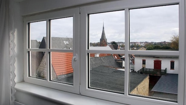 A window with a view of a town, including a church steeple and buildings with red roofs. - Studio with a panoramic view, centrally located in the Old Town, quiet, Wi-Fi, free parking (FL)