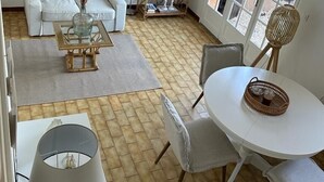 A modern living room with a sofa, coffee table, and dining area with chairs and a table. - Typical house of Provence in quiet surroundings, with breathtaking sea-view (Le Lavandou)