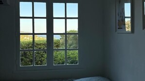 A room with a bed, a window with a view of greenery, and a wall-mounted picture. - Typical house of Provence in quiet surroundings, with breathtaking sea-view (Le Lavandou)