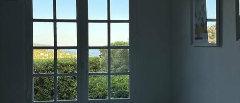Una habitación con cama, ventana con vista a vegetación y un cuerpo de agua, y un aire acondicionado de pared.