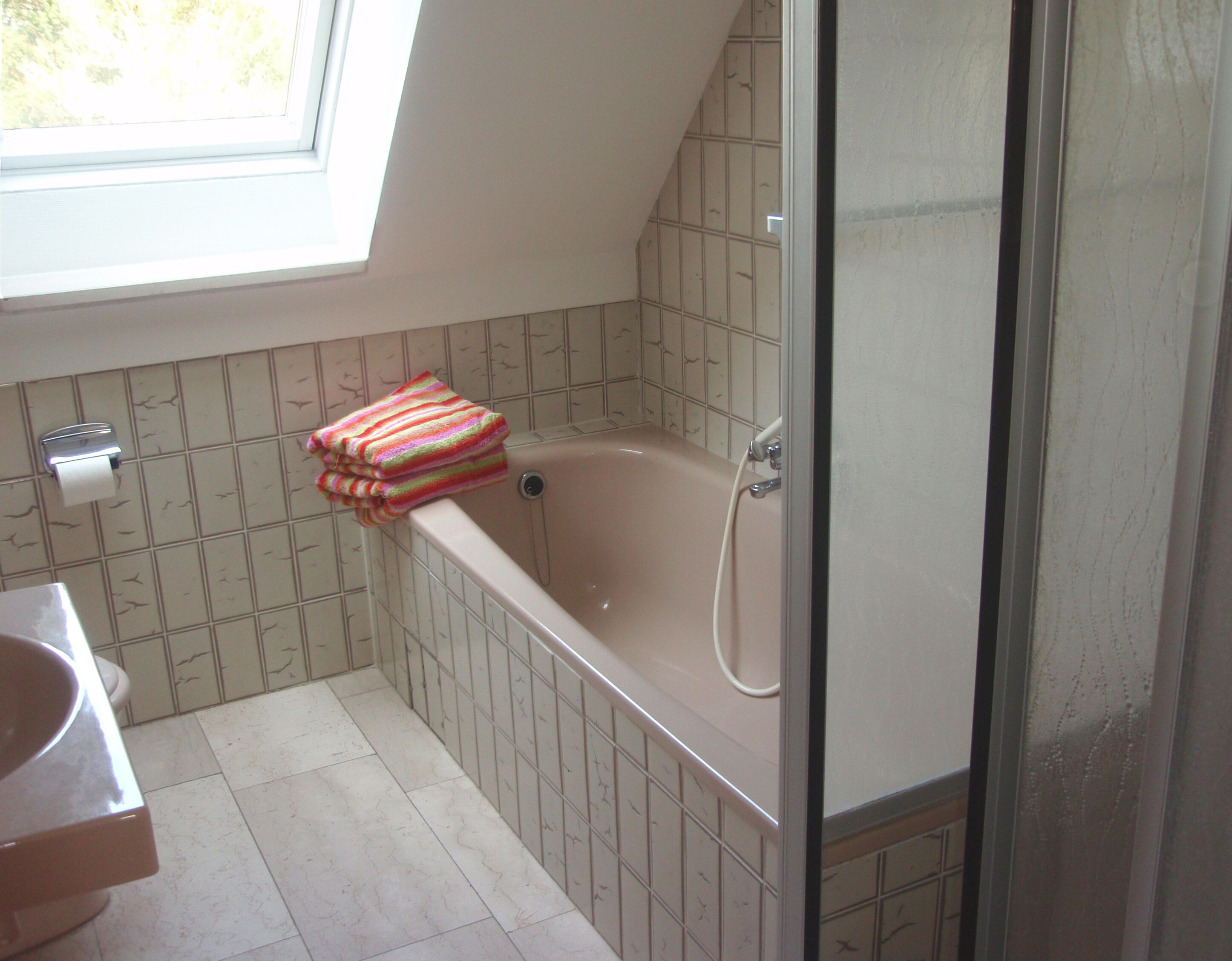 Ein Badezimmer mit Badewanne, Toilette und Fenster.