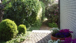 A garden pathway with a brick surface leading to a white building. - Apartment Glücksburg is modern, comfortably furnished in 2017. (Ulsnis)