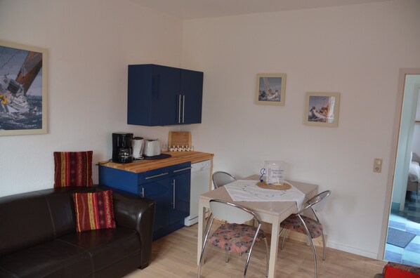 Un espacio habitable compacto con kitchenette, comedor y sofá.