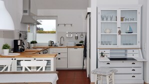 A compact kitchen with white cabinetry, a wooden countertop, and a dining area with a table and chairs.