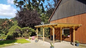 A covered patio area with a pergola, seating, and potted plants. - Country cottage with garden i (Sandbostel)