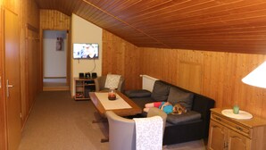 A cozy room with a wooden ceiling, a sofa, a table, and a television. - Country cottage with garden i (Sandbostel)