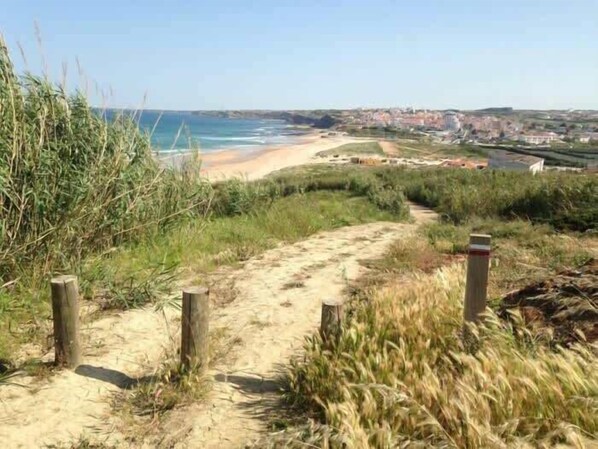 A coastal path leading to a beach with a town in the background. - Casa Azul with Pool and Oceanview (Lourinhã)