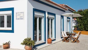 Un edificio con fachada azul y blanca, un letrero que dice 'CASA AGLIA' y un patio con mesa y sillas.