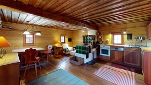 A cozy cabin-style kitchen with wooden walls and a high ceiling. It includes a dining area with a table and chairs, a kitchen counter with appliances, and a small island with a sink. - Find rest - experience nature -Aussteigen on time (Stanz im Mürztal)