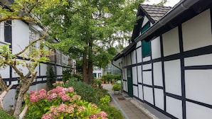 A traditional half-timbered building with a garden pathway and flowering plants. - Idyllic, completely renovated half-timbered house in a listed courtyard (Neunkirchen-Seelscheid)