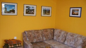 A living room with a sofa, ottoman, and a small table with a decorative item.