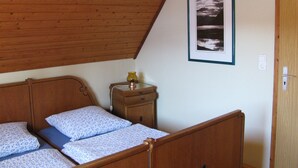 A bedroom with a wooden bunk bed, a bedside table with a lamp, and a framed picture on the wall.