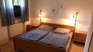 Ein Schlafzimmer mit einem Doppelbett, zwei Nachttischen, einem Heizkörper und zwei Wandlampen.