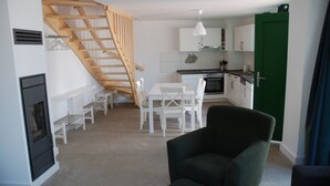 A compact living space with a dining area, kitchen, and a staircase.