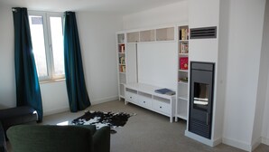 A room with a white built-in bookshelf, a black sofa, a cowhide rug, and a fireplace.