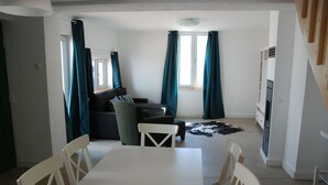 A compact living space with a dining table, chairs, a sofa, and a TV.
