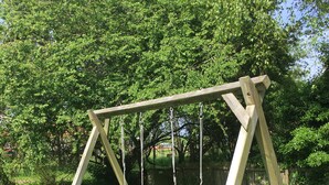 Un'altalena in legno con due onde in un prato.