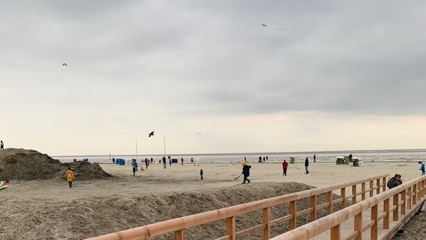 Una passerella di legno conduce a una spiaggia sabbiosa sotto un cielo nuvoloso.