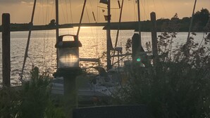 Una marina con diverse imbarcazioni ormeggiate, un molo in legno e uno specchio d'acqua che riflette il tramonto.
