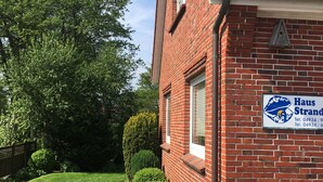 Un edificio in mattoni rossi con una recinzione di legno, cielo sereno e un prato curato.