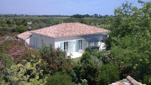 A two-story house with a tiled roof, surrounded by lush greenery and trees. - Pleasant villa seaside with private pool garden 2000m2 (SOLARO)