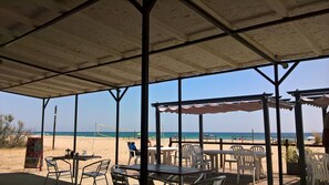Un restaurante frente a la playa con terraza, zona cubierta y vistas al mar.