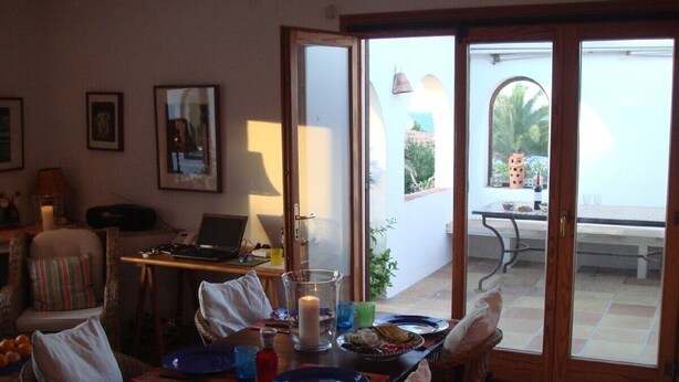 Comedor con una mesa dispuesta para cuatro, un centro de mesa con velas y vista al exterior a través de un ventanal corredero.