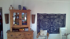 Una habitación con un armario de madera, una silla y un tapiz en la pared.