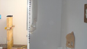 Una habitación con una cama, un estante en la pared y una ventana con cortina.