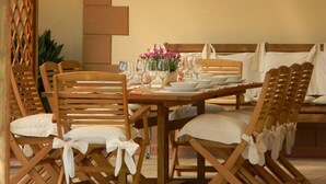 Un coin repas avec une table en bois dressée pour quatre personnes, entourée de chaises en bois dotées de coussins blancs.