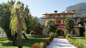 Un bâtiment à deux étages avec un jardin et un chemin qui mène à l’entrée.