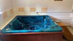 A hot tub with a wooden frame and a blue interior, set against a tiled wall. - Beautiful vacation home on the Baltic Sea coast (Zachodnio Pomorskie Baltic Sea coast)
