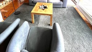 A modern living room with a spiral staircase, a sofa set, and a dining area.