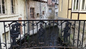 A narrow canal with a decorative metal railing featuring statues of musicians.