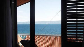 A balcony with a view of the sea, a chair, and a wooden railing. - The apartment is located on the first floor of our house, 50 meters from the sea (Bol)