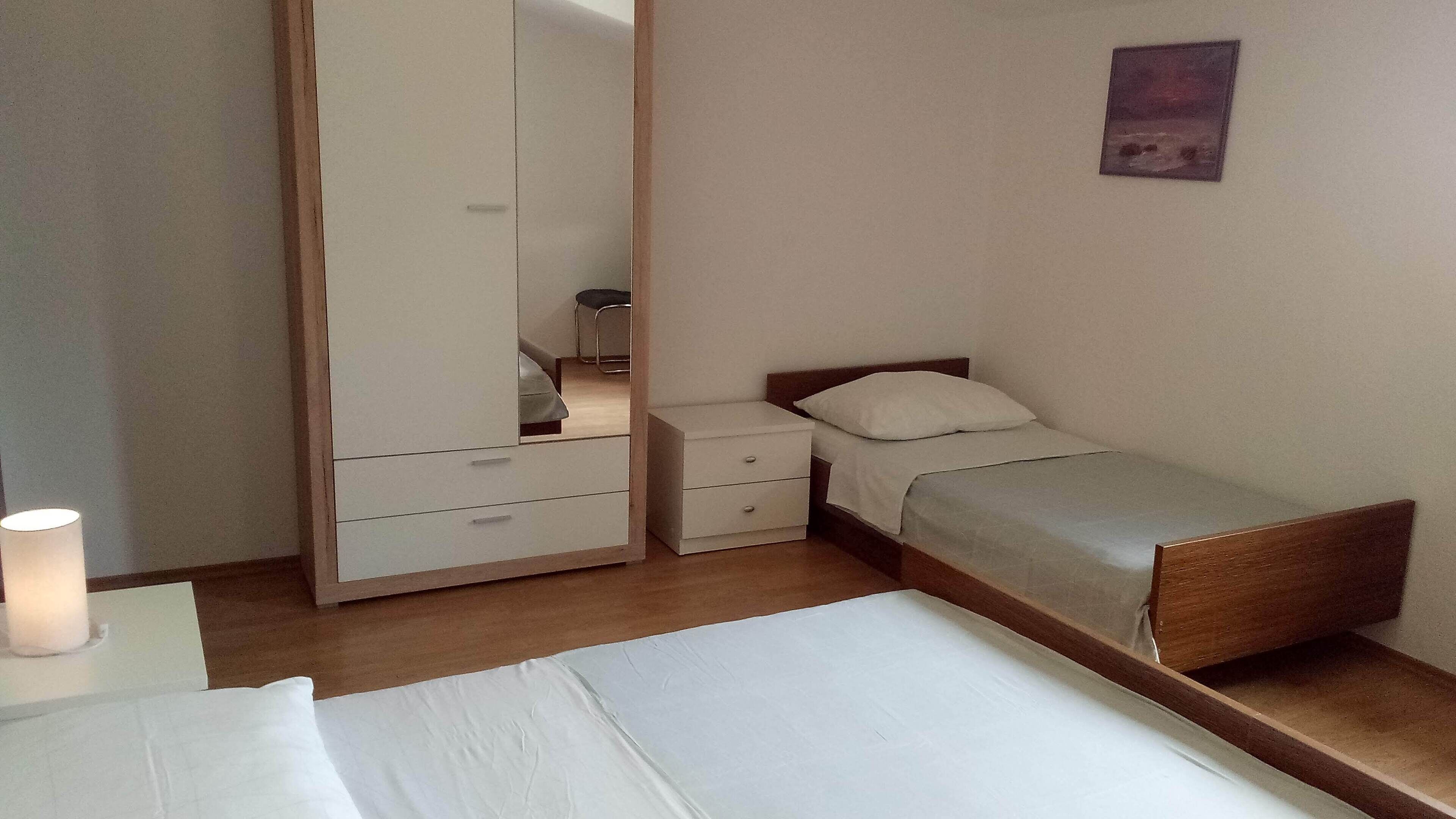 Un dormitorio con cama, mesita de noche, armario y espejo.
