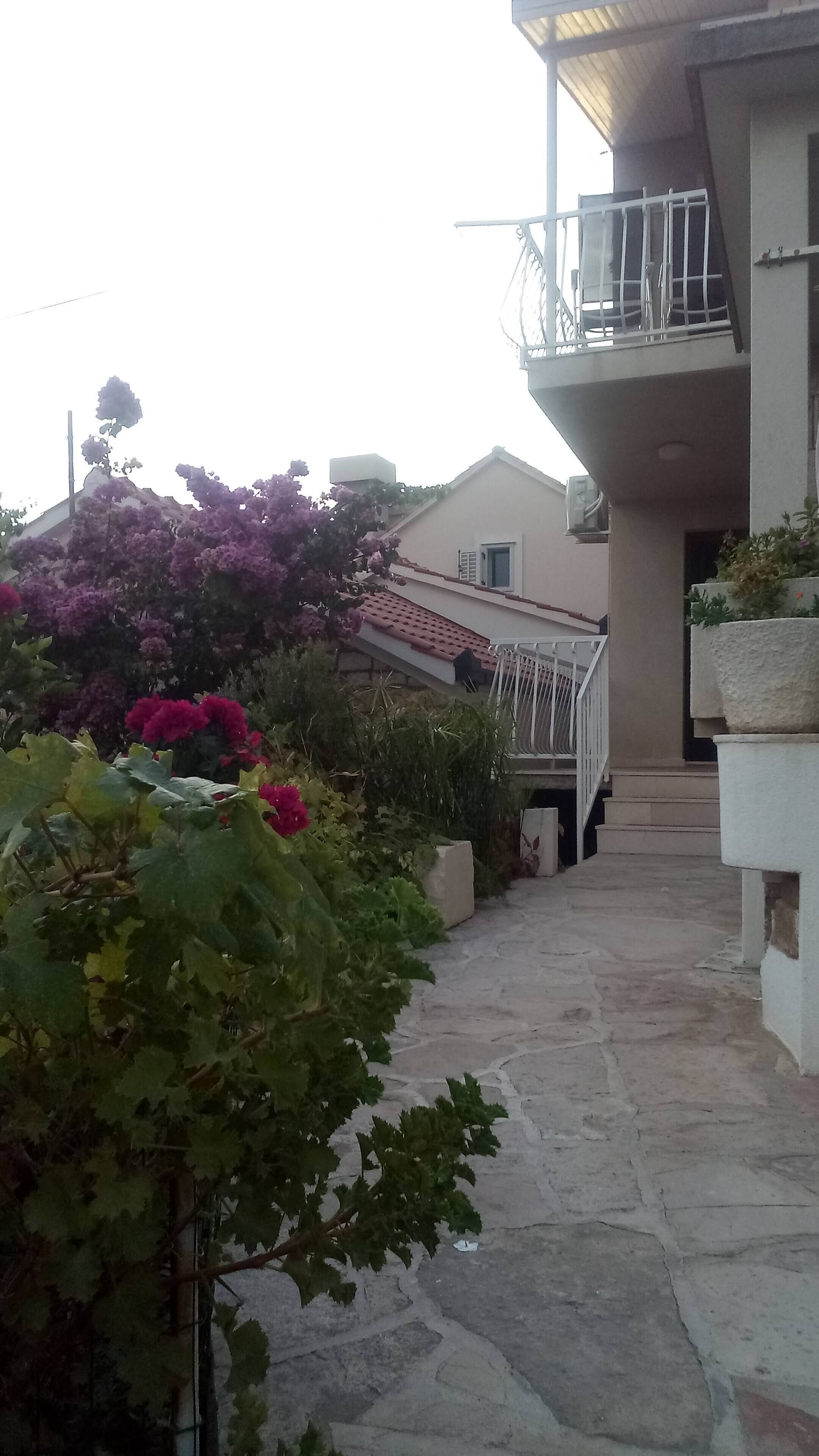 A stone pathway leading to a building with a balcony.