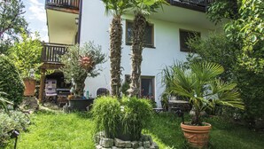 A multi-story building with balconies, surrounded by lush greenery and potted plants. - Lovingly furnished apartment in a Mediterranean style  (Dießen am Ammersee)