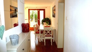 A bright kitchen with a dining area, wooden flooring, and a view through the door. - Lovingly furnished apartment in a Mediterranean style  (Dießen am Ammersee)