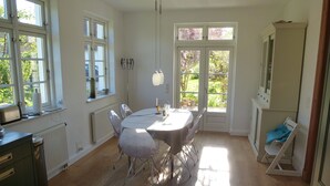 Un comedor con una mesa redonda, sillas y vistas a la vegetación a través de amplios ventanales.