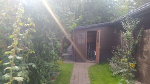 Un chemin de jardin mène à un abri en bois dans lequel se trouve un vélo.