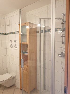 Un baño moderno con tocador de madera, cabina de ducha de vidrio y suelo de baldosas.