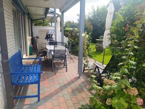 A covered patio area with outdoor furniture, a table, and chairs. - Comfortable, ground-floor vacation apartment with terrace and garden to make you feel at home. (24217 Schönberger Strand)