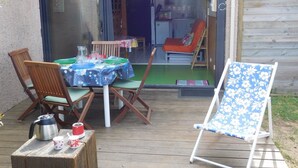 Eine Terrasse im Freien mit Tisch, Stühlen, einem Klappstuhl und einer kleinen Holzterrasse.