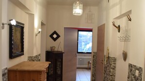 A hallway with a wooden cabinet, a red rug, a hanging light fixture, and a view through an open door. - MESSE + Airport Nuremberg - Fürth - Erlangen - Bamberg - Rest Nature - Time out (Lauf an der Pegnitz)