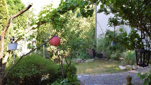 A garden pathway with a stone pavement, surrounded by greenery and a metal fence. - MESSE + Airport Nuremberg - Fürth - Erlangen - Bamberg - Rest Nature - Time out (Lauf an der Pegnitz)