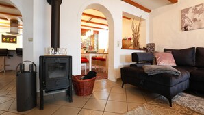 A living room with a black wood-burning stove, a black sofa, and a red wicker basket. - 4 star holiday home "Zum Weiher" 160sqm in the heart of the Hunsrück-Hochwald National Park  (Allenbach)