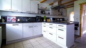A modern kitchen with white cabinets, a black countertop, and a built-in stove. - 4 star holiday home "Zum Weiher" 160sqm in the heart of the Hunsrück-Hochwald National Park  (Allenbach)
