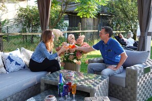 Een terras met rieten meubels en een geruit tafeltje.